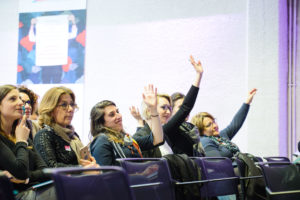 femmes levant la main à une conférence