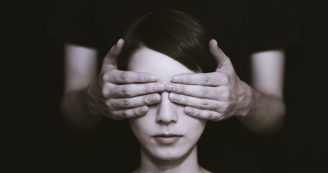 Femme aux yeux masqués par des mains