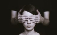 Femme aux yeux masqués par des mains